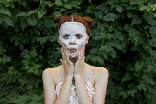 Портрет девушки Антиморщинистая маска Удивлен, чтобы коснуться вашего лица с вашими руками по уходу за кожей кусты на заднем плане — стоковое фото