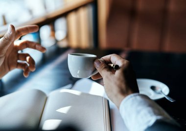 Bir adam elinde kahve fincanı tutuyor. Kalem defterleri, kafe.