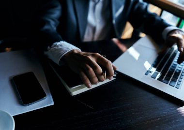 Takım elbiseli bir iş adamı bir kafede ya da dizüstü bilgisayarla oturuyor.