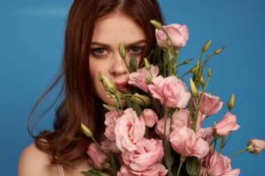 Mavi arka plan modelinde pembe çiçekleri olan güzel bir kadın. 