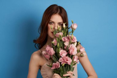 Mavi arka plan modelinde pembe çiçekleri olan güzel bir kadın. 