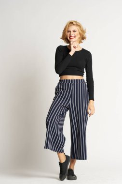 Siyah kazaklı, çizgili pantolonlu, güzel bir kadın. Moda kıyafetleri arka planda.