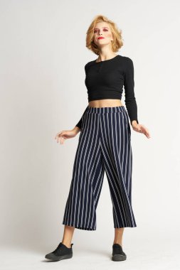 Siyah kazaklı, çizgili pantolonlu, güzel bir kadın. Moda kıyafetleri arka planda.