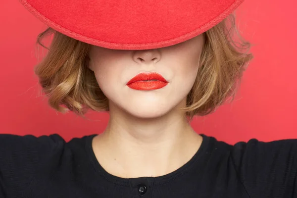 Woman covers with hat her eyes red lips close-up isolated background