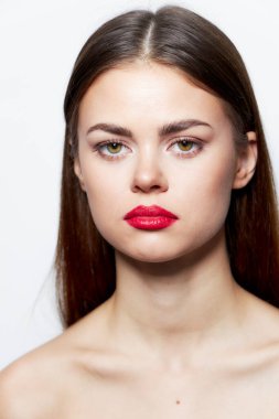 Kız ileriye bakıyor. Çıplak omuzlar. Saf ten rengi, kırmızı dudaklar. 