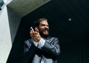 Takım elbiseli bir iş adamı açık hava işletmecisiyle telefonda konuşuyor.