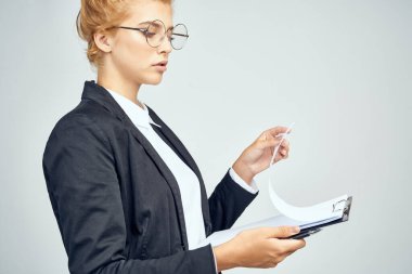 Resmi bir iş kadınının takım elbisesi içindeki bir kadın bir iş dosyasına belge koyuyor.