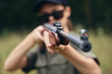Dışarıda namlunun ucunda silah avlayan bir kadın var.