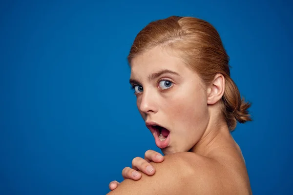 Donna con la pelle pulita spalle nude emozioni blu sfondo modello cura del viso — Foto Stock