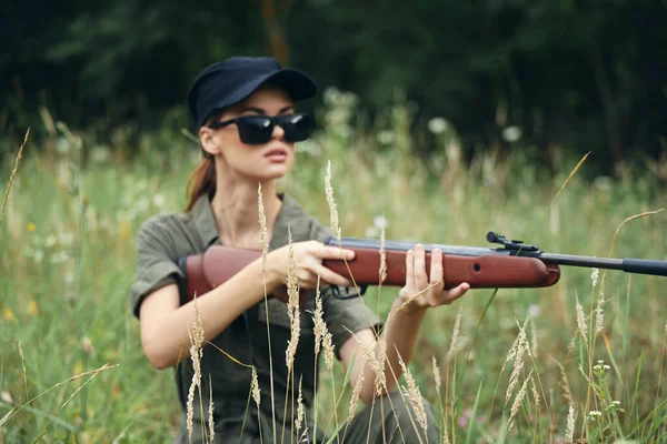 Mujer al aire libre en gafas oscuras con armas refugio caza hojas verdes árboles verdes — Foto de Stock