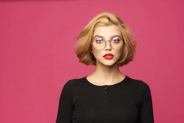 Mujer bonita en suéter negro gafas de peinado corto rosa aislado fondo —  Fotos de Stock