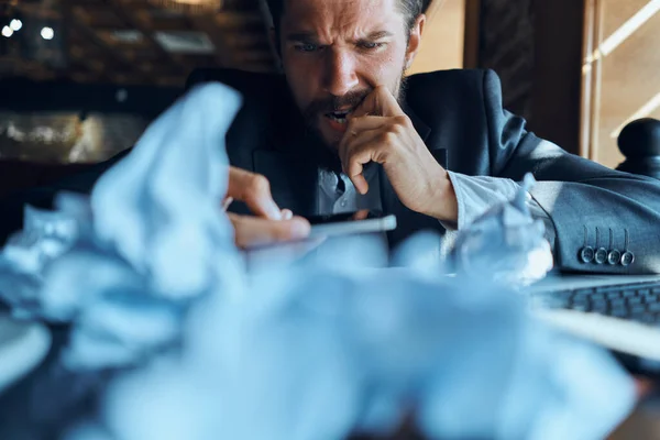 Geschäftsmann sitzt am Tisch vor zerknülltem Laptop — Stockfoto