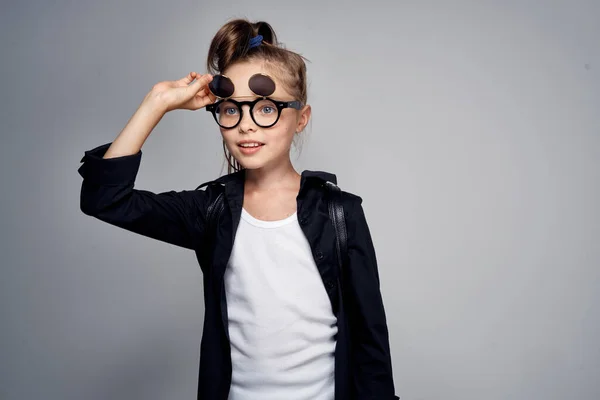 Schattig schoolmeisje dragen zonnebril jeugd leren school licht achtergrond — Stockfoto