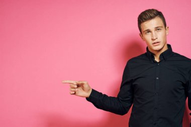 Siyah gömlekli adam el hareketleriyle yaşam tarzını pembe izole bir arkaplan.