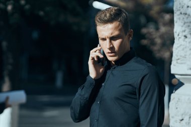 Elinde belgelerle binanın yanında tişörtlü bir iş adamı.