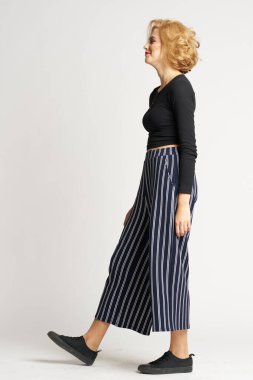 Siyah kazaklı, çizgili pantolonlu, güzel bir kadın. Moda kıyafetleri arka planda.