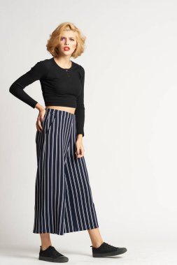 Siyah kazaklı, çizgili pantolonlu, güzel bir kadın. Moda kıyafetleri arka planda.