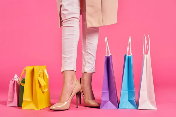 Sacos de compras pés femininos em sapatos Shopaholic fundo rosa — Fotografia de Stock