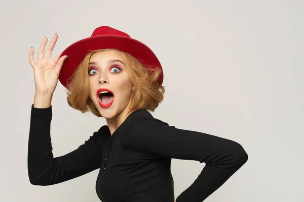 빨간 모자를 쓰고 붉은 입술을 하고 있는 유행적 인 여자가 밝은 배경 감정을 보고 있다 — 스톡 사진