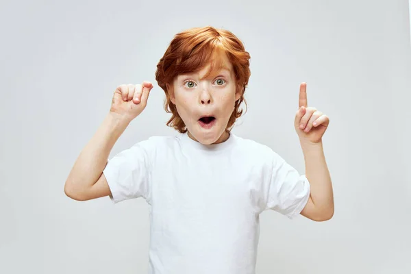 Surprised child with open mouth red hair white tee shirt