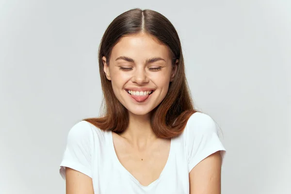 Γυναίκα σε λευκό T-shirt γελάει με κλειστά μάτια και προεξέχει γλώσσα προς τα εμπρός — Φωτογραφία Αρχείου