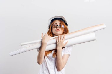 Beyaz korumalı miğferli kadın ellerinde planlar mimari iş aydınlatma arka planıyla