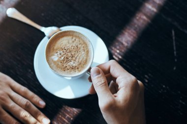 Masanın üzerinde beyaz pirinç ve bir çay kaşığı kafe erkeği eli olan bir fincan kahve..