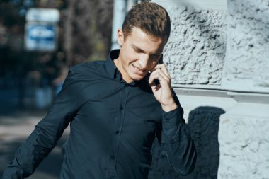 Elinde belgelerle binanın yanında tişörtlü bir iş adamı.