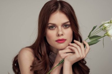 Elinde çiçekle parlak bir arka planı olan bir kadın.