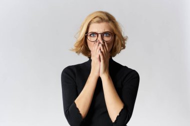 Gözlüklü, sarışın, kırmızı dudaklı, siyah bluzlu, göz kamaştırıcı ışıklı arka plan stüdyosu olan bir kız.