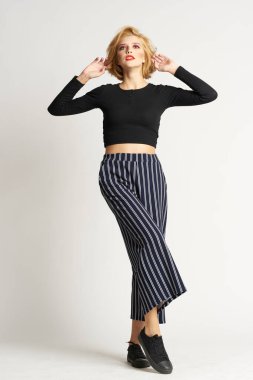 Siyah kazaklı, çizgili pantolonlu, güzel bir kadın. Moda kıyafetleri arka planda.