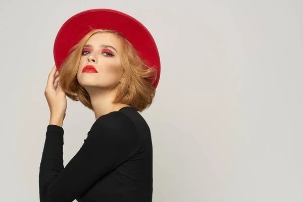 La mujer a la moda en rojo sombrero negro blusa rojo labios recortados ver luz fondo emociones — Foto de Stock