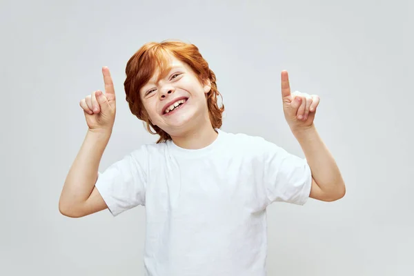 Rudowłosy chłopiec pokazuje palec wskazujący w górę Kopiuj przestrzeń — Zdjęcie stockowe