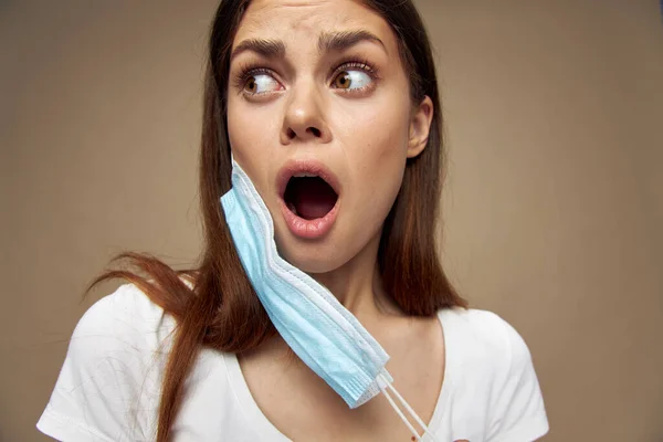 Mujer asustada con una máscara médica en la cara mira a los lados camiseta blanca — Foto de Stock