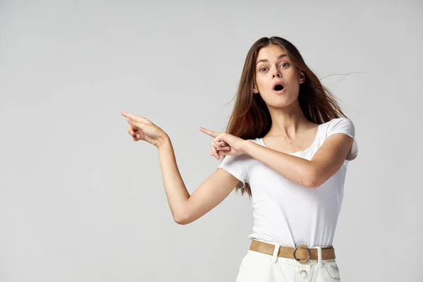 Mulher emocional com a boca aberta mostra os dedos para o lado de uma camiseta branca Espaço Copiar — Fotografia de Stock