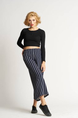 Siyah kazaklı, çizgili pantolonlu, güzel bir kadın. Moda kıyafetleri arka planda.