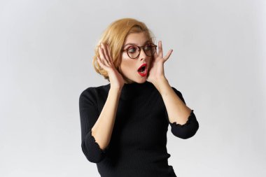 Gözlüklü, sarışın, kırmızı dudaklı, siyah bluzlu, göz kamaştırıcı ışıklı arka plan stüdyosu olan bir kız.