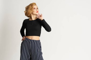 Siyah kazaklı, çizgili pantolonlu, güzel bir kadın. Moda kıyafetleri arka planda.