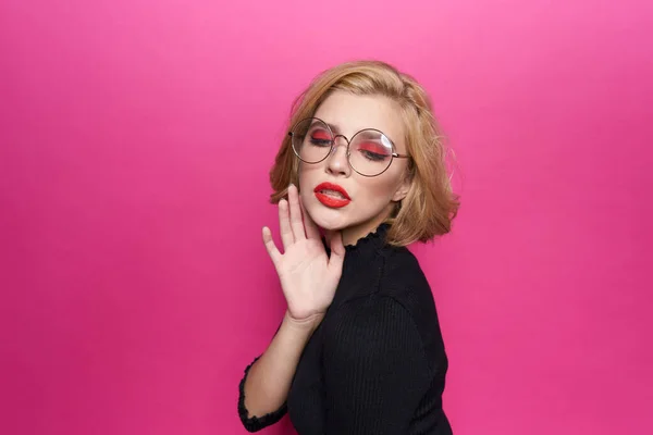 Mujer bonita en suéter negro labios rojos en gafas emociones fondo rosa —  Fotos de Stock