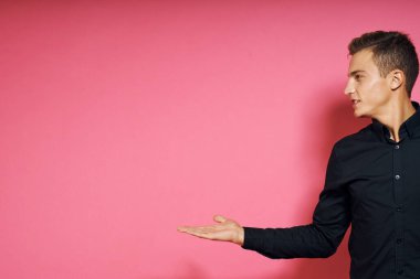 Siyah gömlekli adam el hareketleriyle yaşam tarzını pembe izole bir arkaplan.