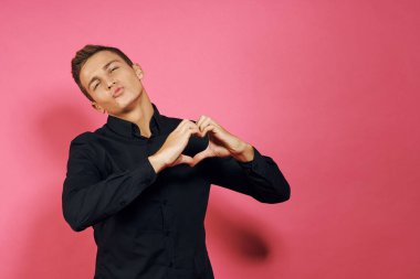 Siyah gömlekli adam el hareketleriyle yaşam tarzını pembe izole bir arkaplan.