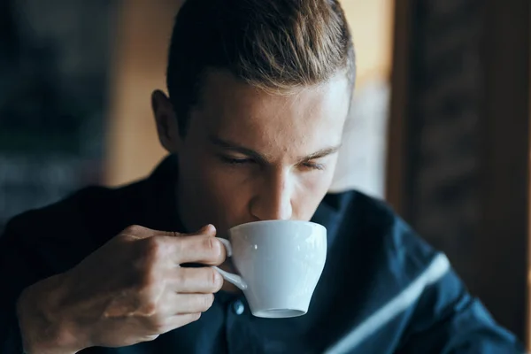 Affärsman med en kopp kaffe i ett café och en mörk skjorta stilig ansikte — Stockfoto