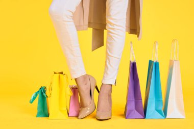 Ayakkabılı kadın ayakları alışveriş tarzı sarı izole bir arka plan.