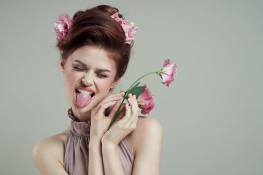 Güzel bir kadın, dili kapalı gözlerle, çiçekleri parlak makyaj dekorasyonu, ışık arka planı gösterir.