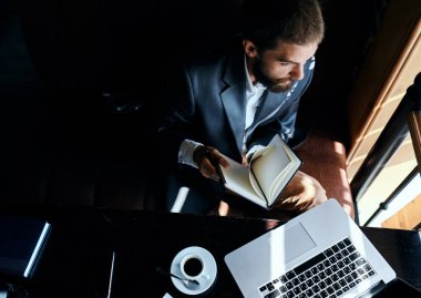 İş adamı bir kafede dizüstü bilgisayarın önünde oturuyor. Elinde bir fincan kahve işi teknolojisi yaşam tarzı var.