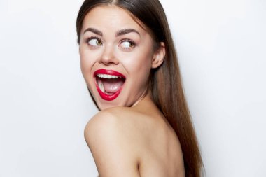 Omuzları açık, ağzı açık bir kadın kırmızı dudaklı spa tedavisine doğru bakıyor. 