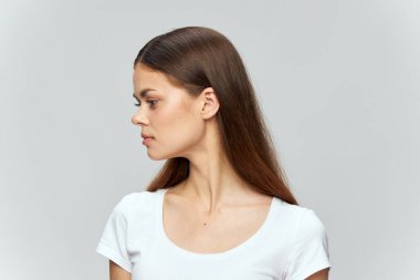 Tişört giymiş genç bir kadının portresi başını yana çevirmiş. 