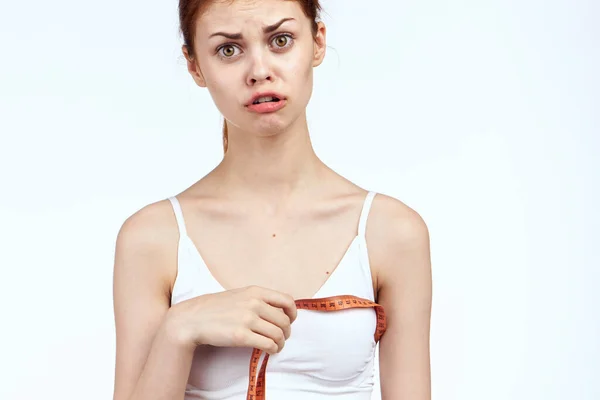 Mulher com fita métrica em branco t-shirt saúde luz fundo — Fotografia de Stock