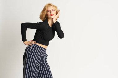 Siyah kazaklı, çizgili pantolonlu, güzel bir kadın. Moda kıyafetleri arka planda.