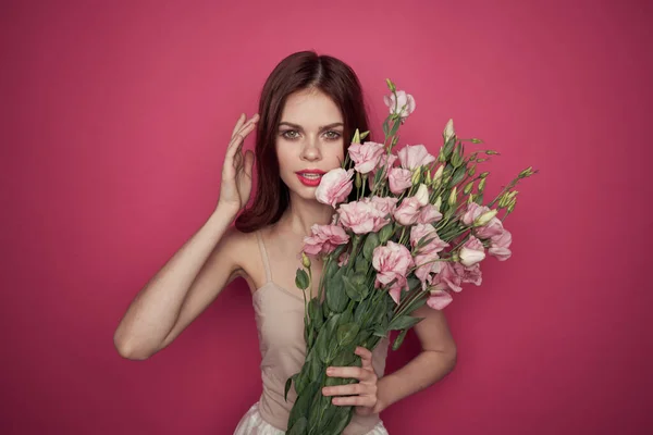 Piękna kobieta z bukietem kwiatów na różowym tle w lekkim modelu makijażu sukienka — Zdjęcie stockowe